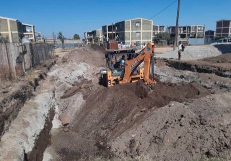 A backhoe excavating a treatment basin between condominium blocks