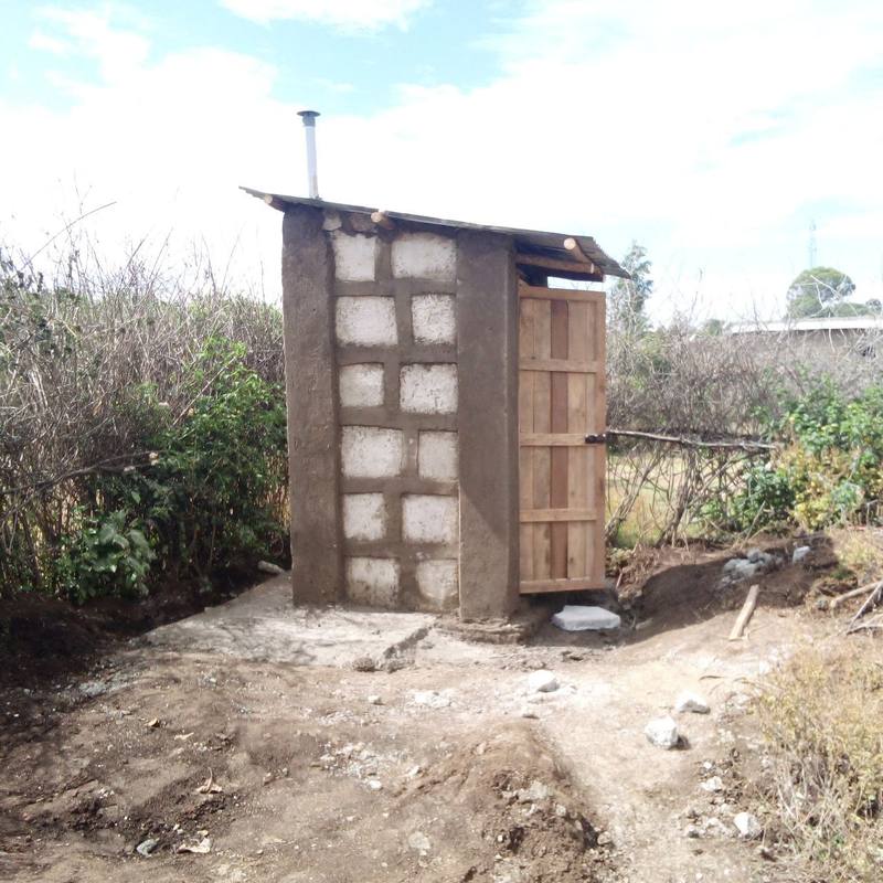 A completed household toilet with interlocking panel walls, a wooden door and a vent pipe